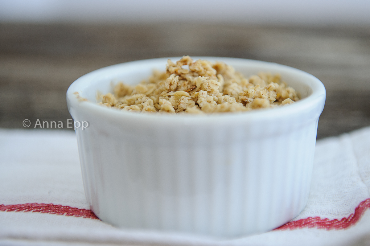 Baked Apple Crisp in a white ramkin, sitting on a white napkin with red ribbing.